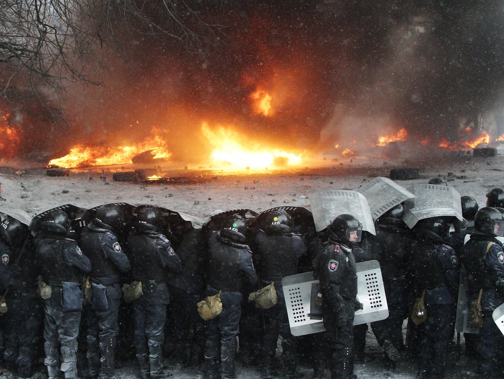 The policemen held up shields to block themselves from falling ashes.