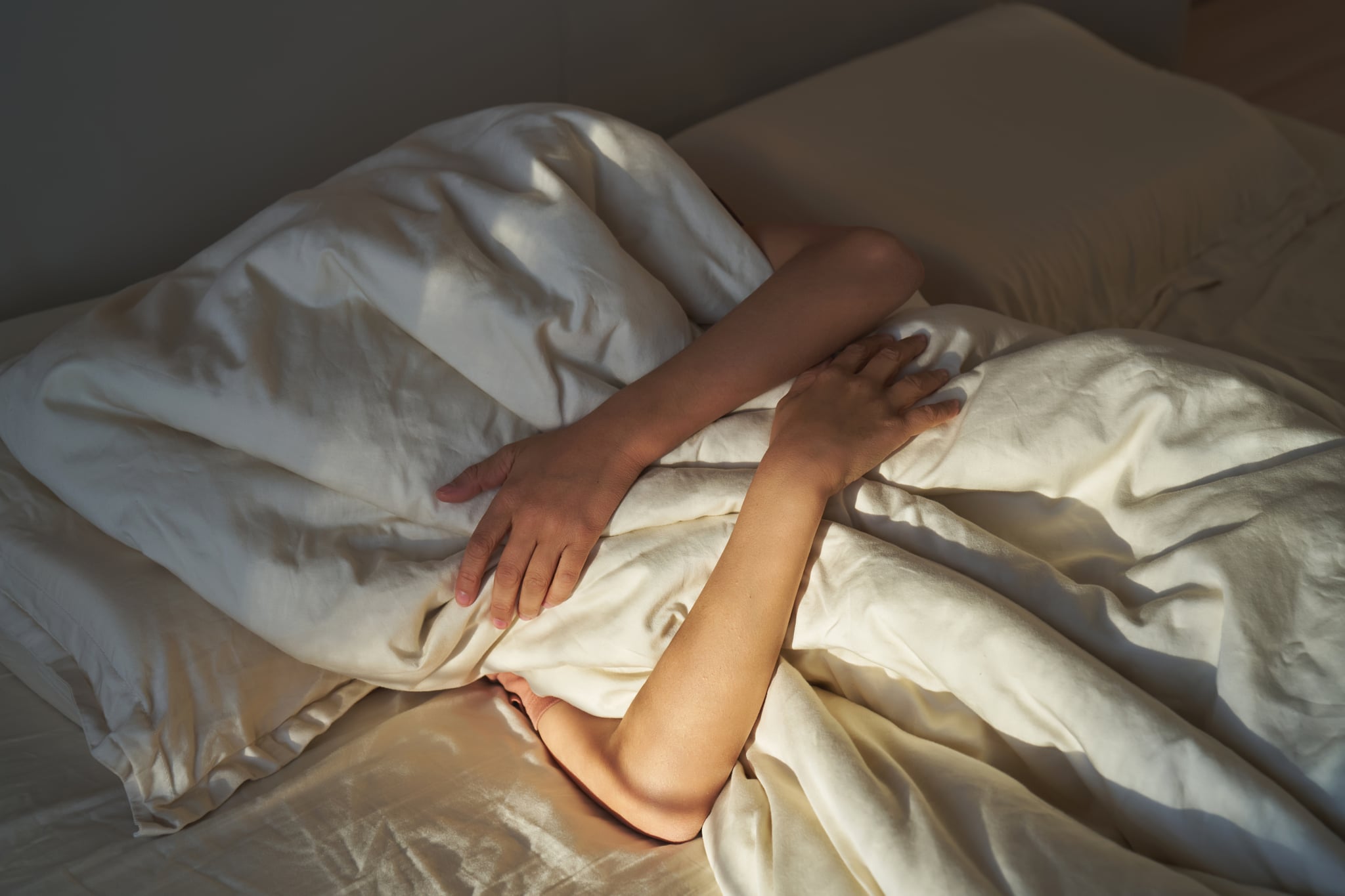 Person hiding under a comforter in bed