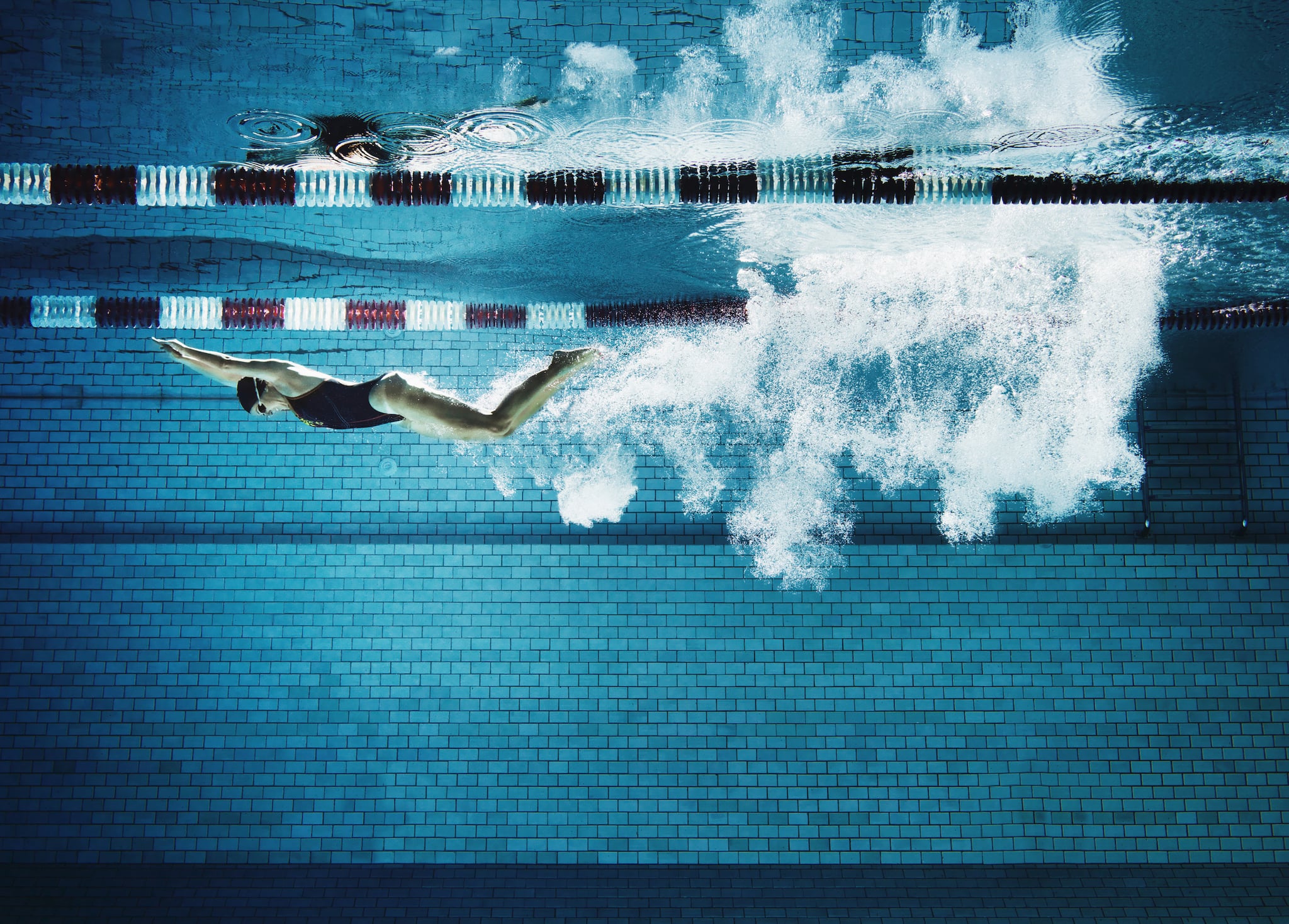 Underwater view of adult female swimmer having broken the water surface with dive