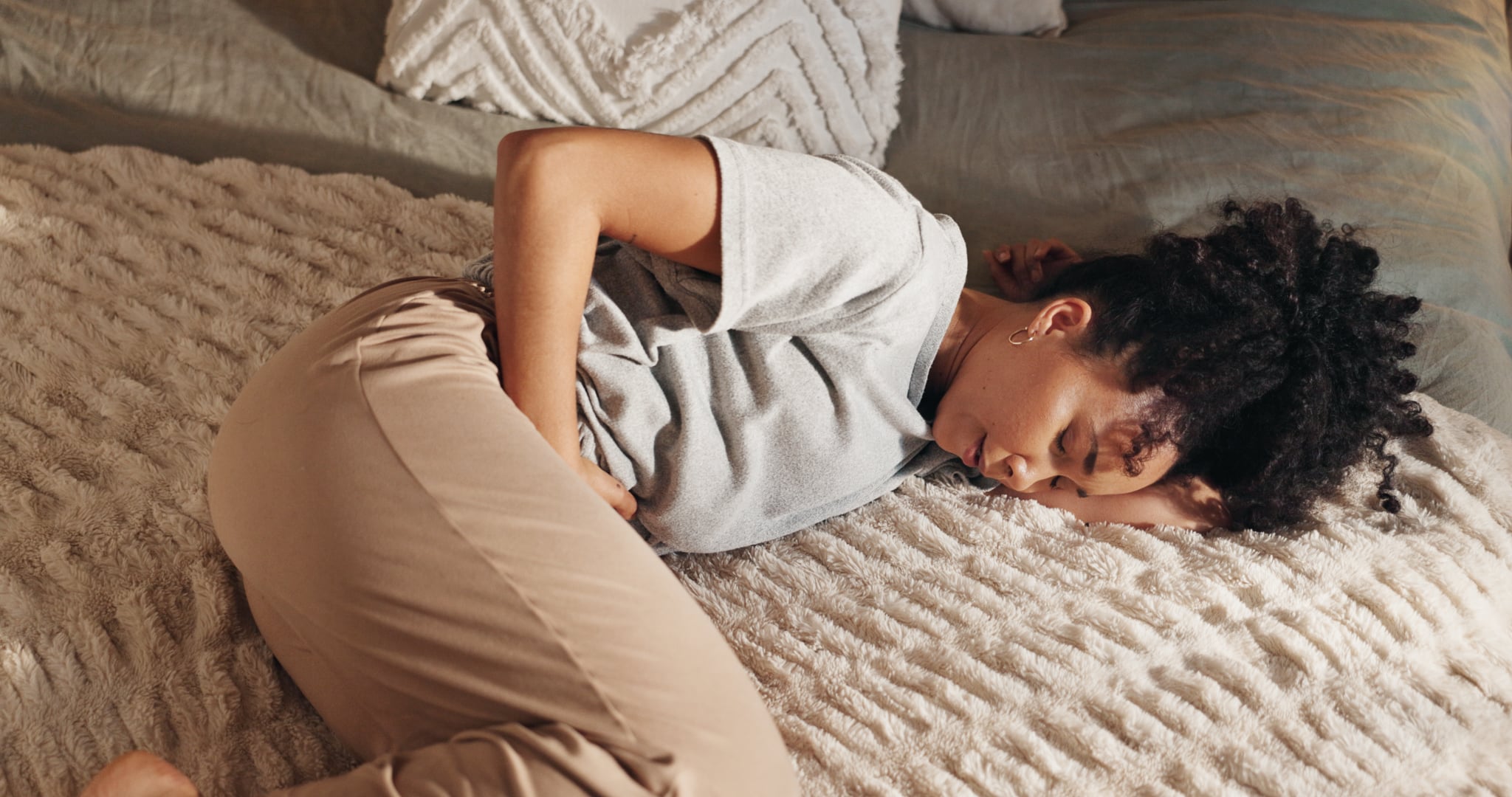 Woman lying in bed, cramps after masturbating.
