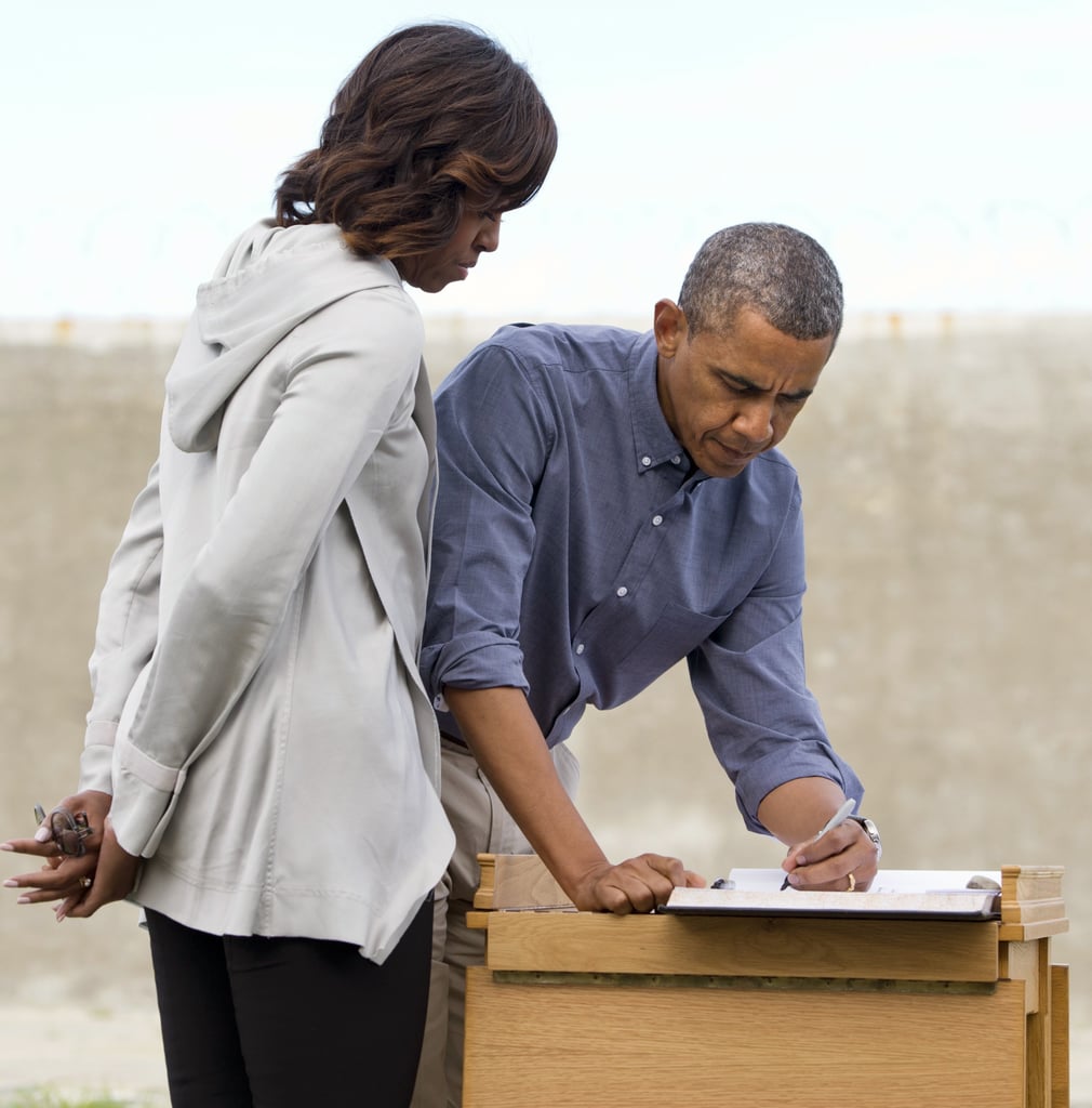 First Lady Michelle Obama looked on as President Obama signed a guest book in the Robben Island prison yard outside Cape Town, South Africa, in June 2013.