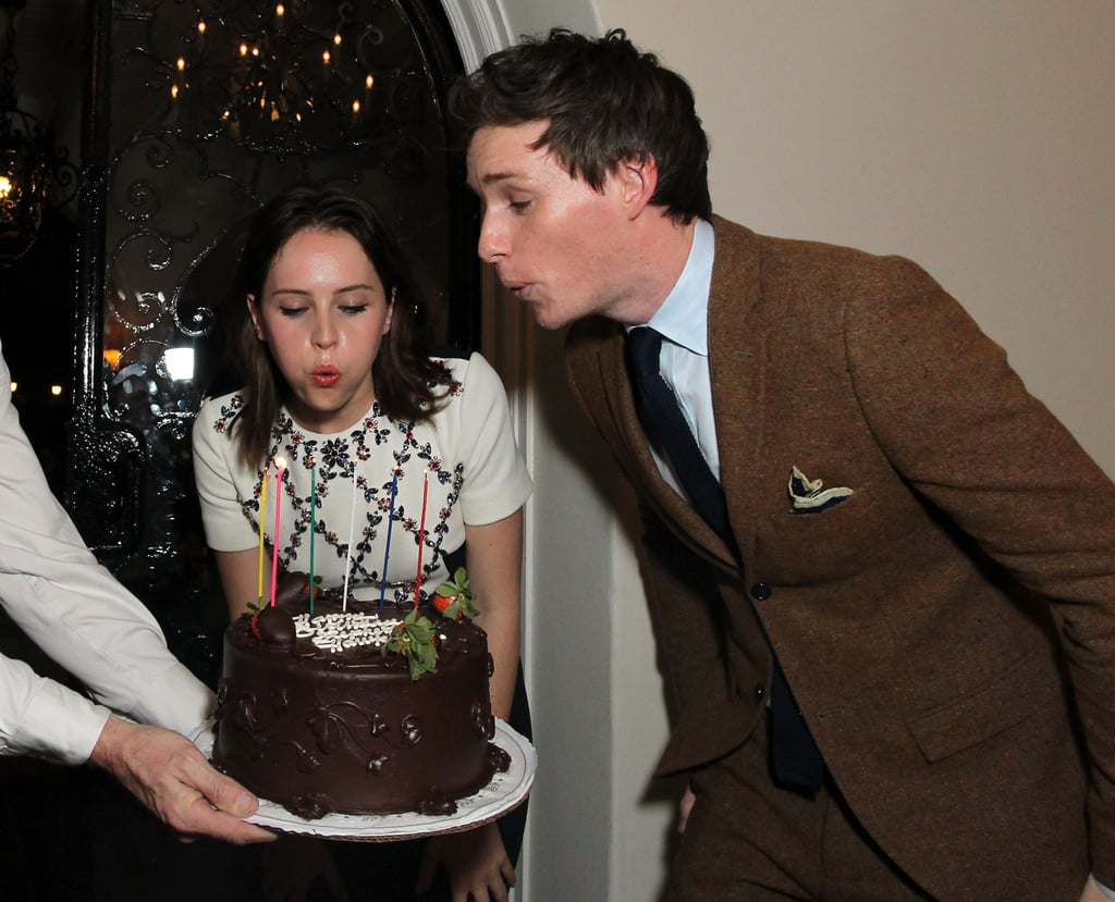 Birthday boy Eddie Redmayne got help from his The Theory of Everything costar Felicity Jones to blow out the candles on his cake at the British Consulate-General Focus Features Golden Globes bash in LA.