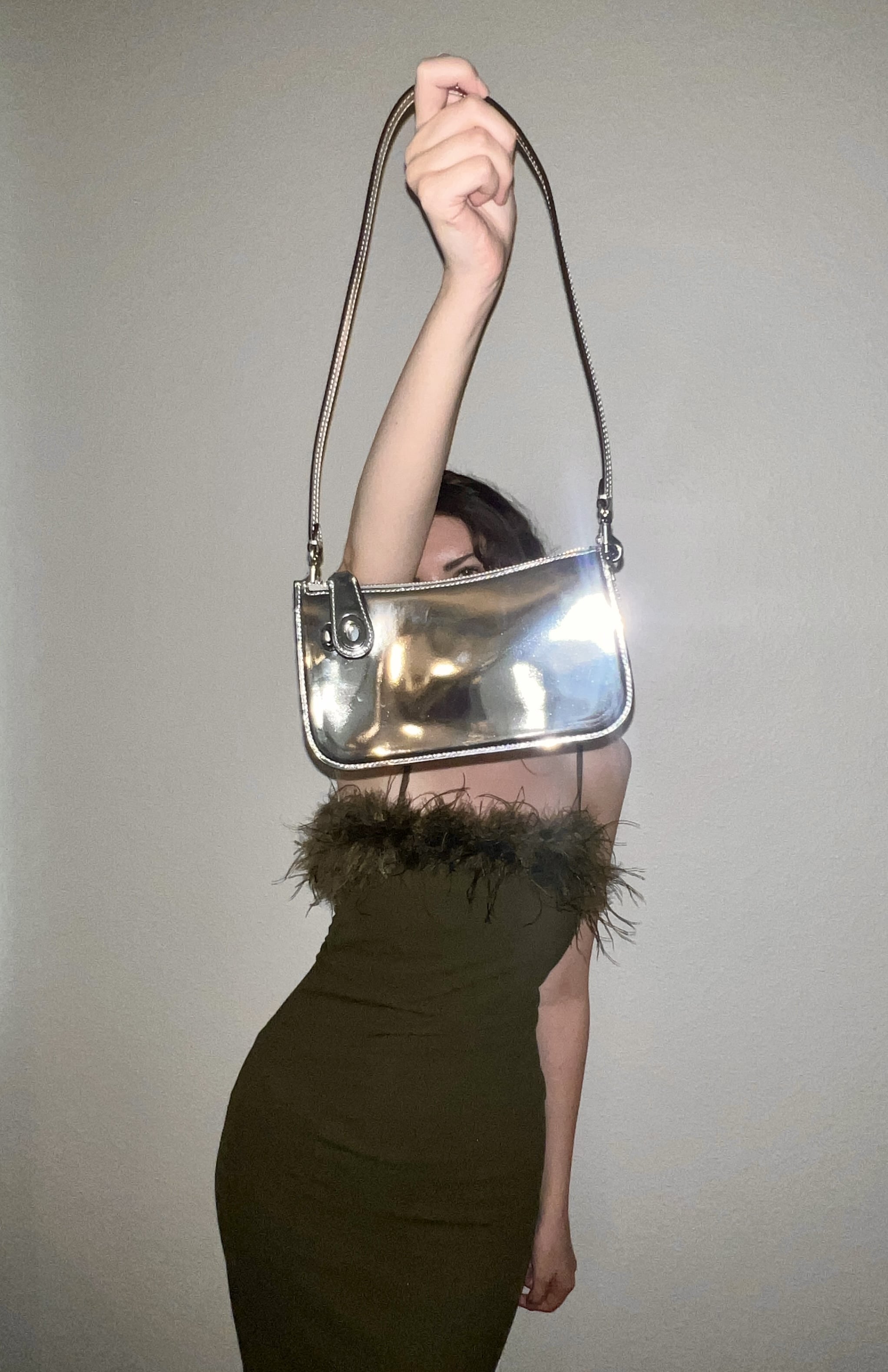 woman holding the coach metallic penn shoulder bag