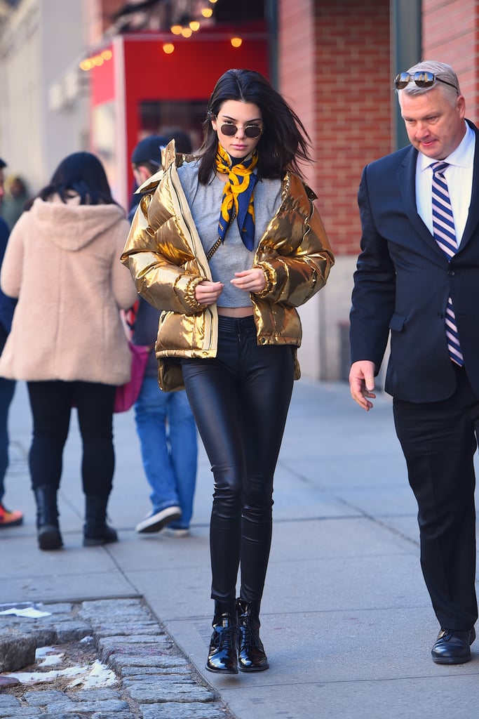 Kendall Jenner styled her metallic Ports 1961 puffer jacket with a gold silk scarf.