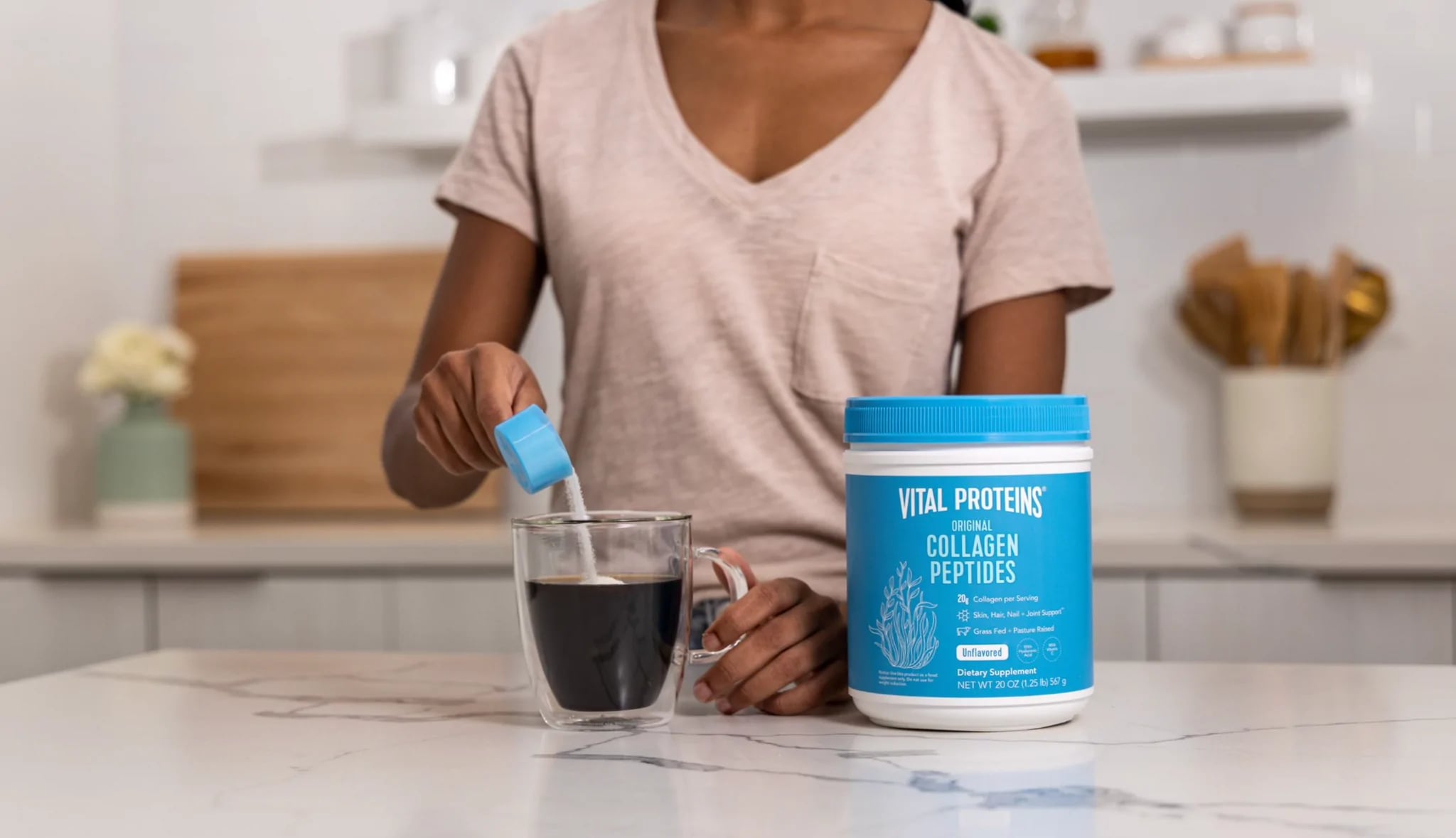 Woman pouring Vital Proteins Collagen Peptides Powder into coffee cup.