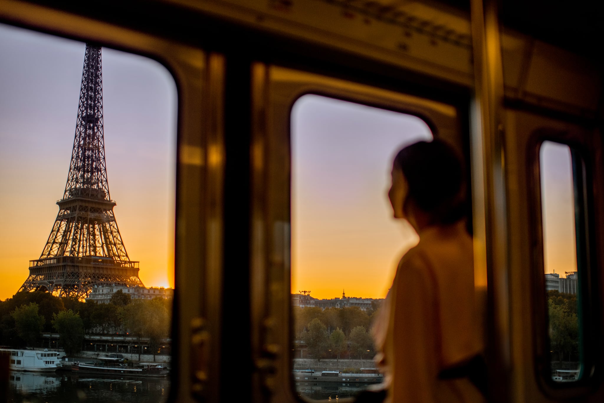 Young woman enjoying view on the Eiffel tower from the subway train during the sunrise in Paris