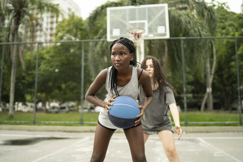 Female friends playng basketball in a public park in Brazil