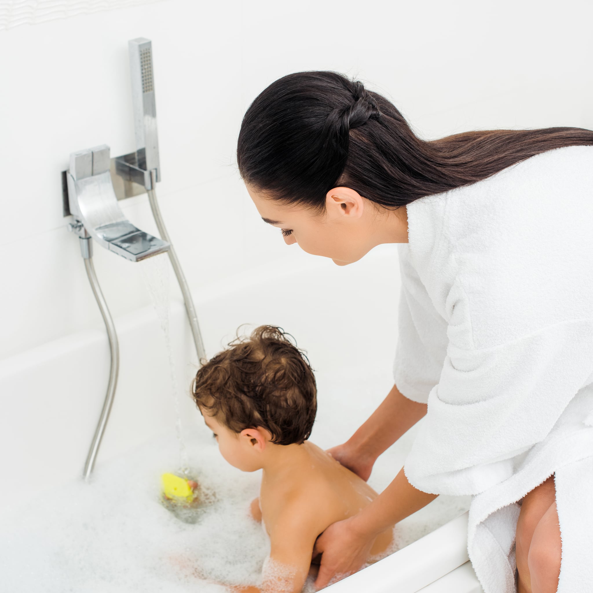 Mom in bathrobe washing son in white bathroom; Shutterstock ID 1234308316; Job: -