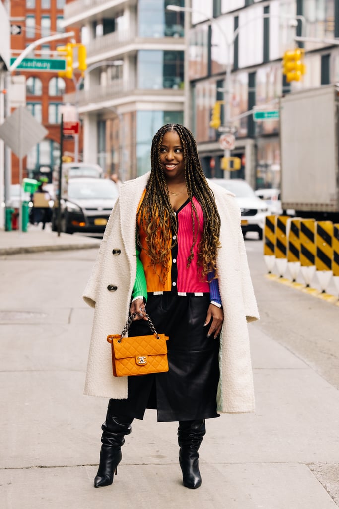 Jessica Andrews wears a vibrant colour block ribbed Christopher John Rogers cardigan and a Tibi skirt from Hampden, an orange quilted Chanel bag from Vivrelle, black boots from Flor de Maria, and checkered nails from B-Clawed.