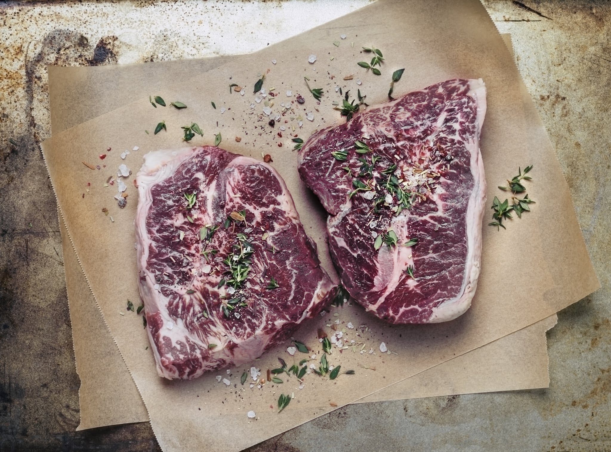 Two pieces of raw steak on parchment paper