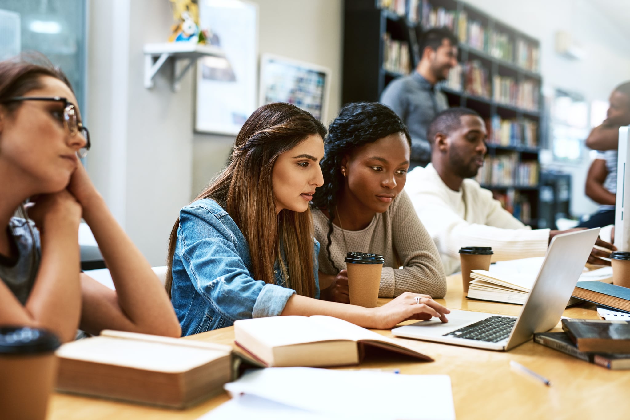 Shot of two young women using a laptop together in a college library