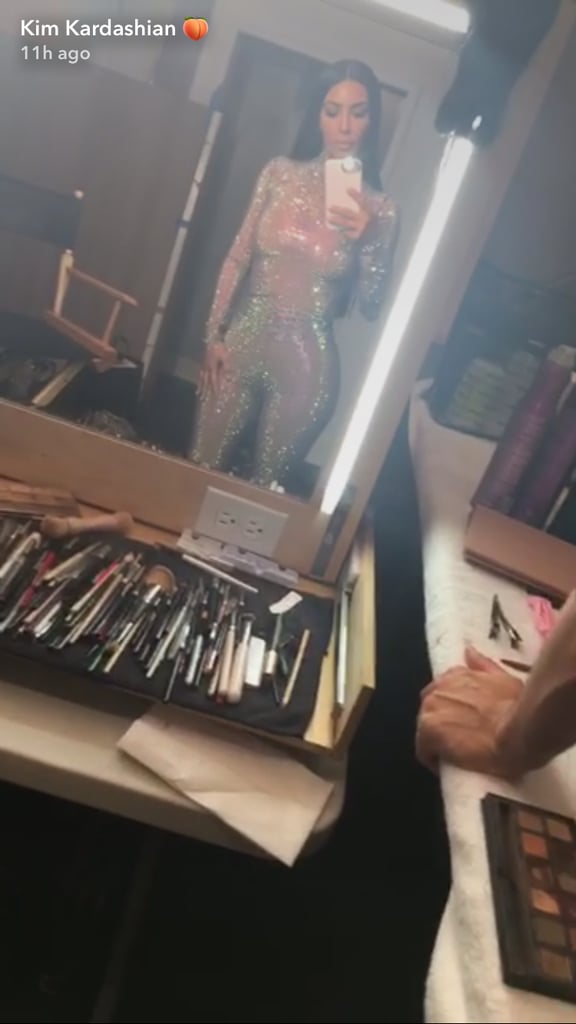 It should come as no surprise that Kim Kardashian is working on something secretive yet again. After teasing her upcoming KKW Beauty launch, the multi-hyphenate shared some behind-the-scenes footage from an undisclosed photo shoot. In the videos shared with her followers, Kim is wearing a head-to-toe bedazzled bodysuit.
Kim snapped various videos of herself getting ready for the shoot. Before slipping into the crystallized bodysuit, Kim shared a video of herself wearing shapewear and said, "Set vibes." She later posed in front of a mirror while wearing the showstopping ensemble. The bodysuit comes from Gucci's Fall 2017 collection and is actually comprised of a crystal net top and matching leggings that retail for a combined $7,180. Rihanna famously sported the entire runway look — face mask included — at Coachella.
In addition to Kim's videos, makeup artist Mario Dedivanovic shared a seductive video of Kim strutting it in front of a pool. In his Instagram caption, Mario simply said, "She glows." While we await additional details about this flashy shoot, browse pictures of Kim in the blinding bodysuit ahead.