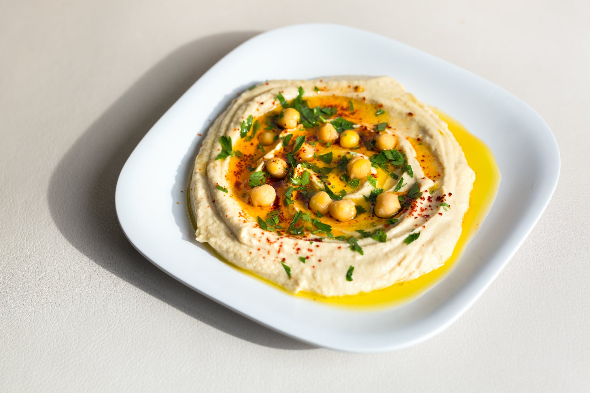 Homemade hummus -  chickpea spread with tahini - on white background; is hummus good for you?
