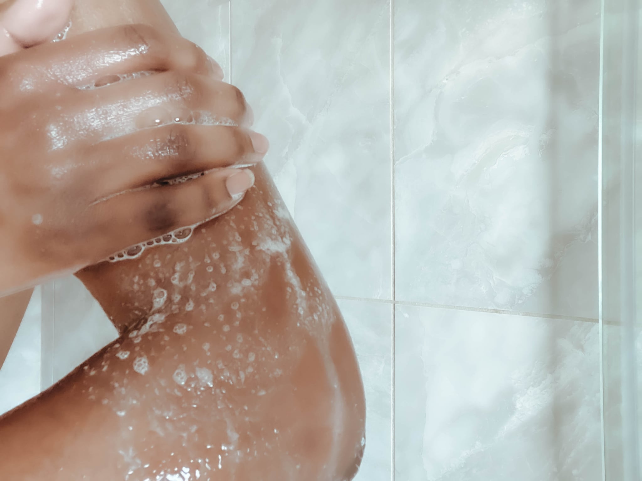 Close-up of unrecognisable woman washing upper body in shower