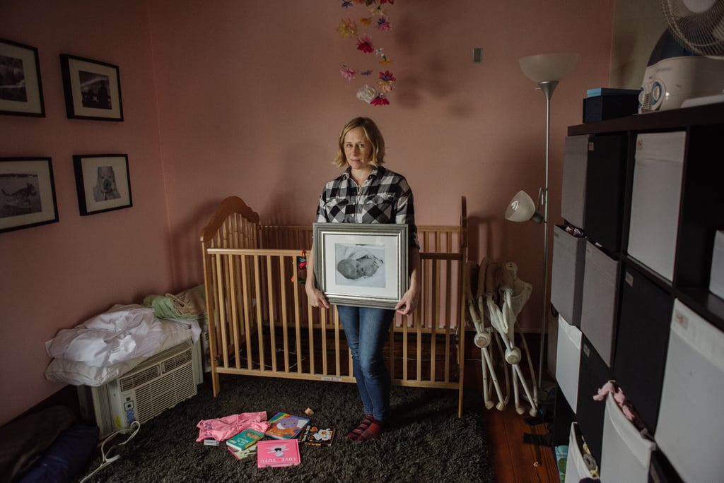 "Kristin holds a photo of her daughter, Abby, in her unfinished nursery. Her death was unexpected and traumatic. Instead of finishing Abby's nursery, the room became a chaotic storage area, mirroring the chaos her death brought into their family."