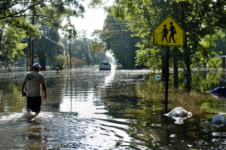 A man in Gonzales, LA walks down his flooded street to assess his home's damage.