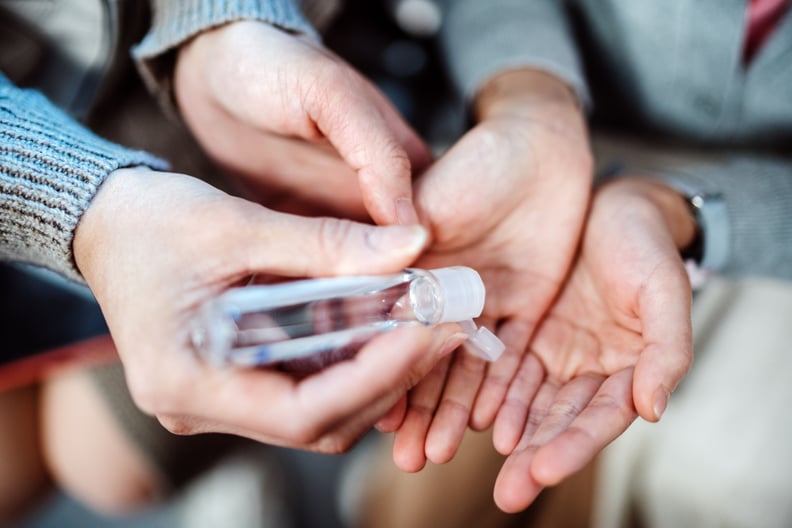 Mom squeezing hand sanitizer onto littler daughter's hands