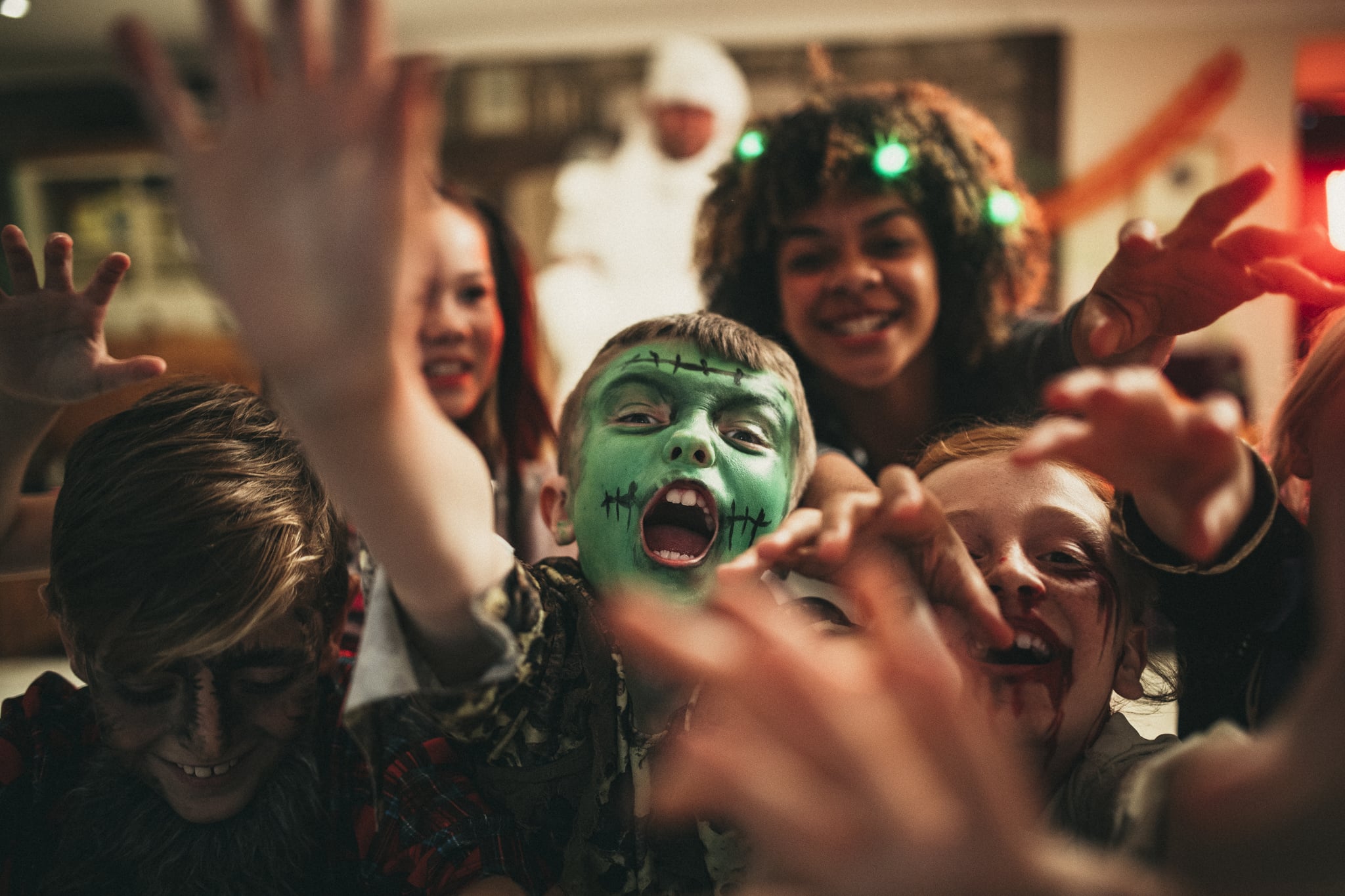 Group of young friends dressed in costumes reaching out towards the camera like zombies.