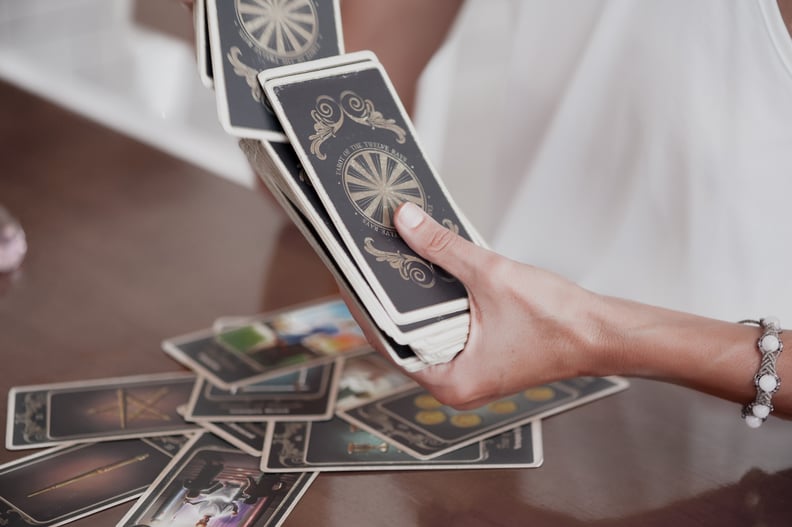 A woman reads Tarot cards on the table in cafe, only her hands visible holding the cards.