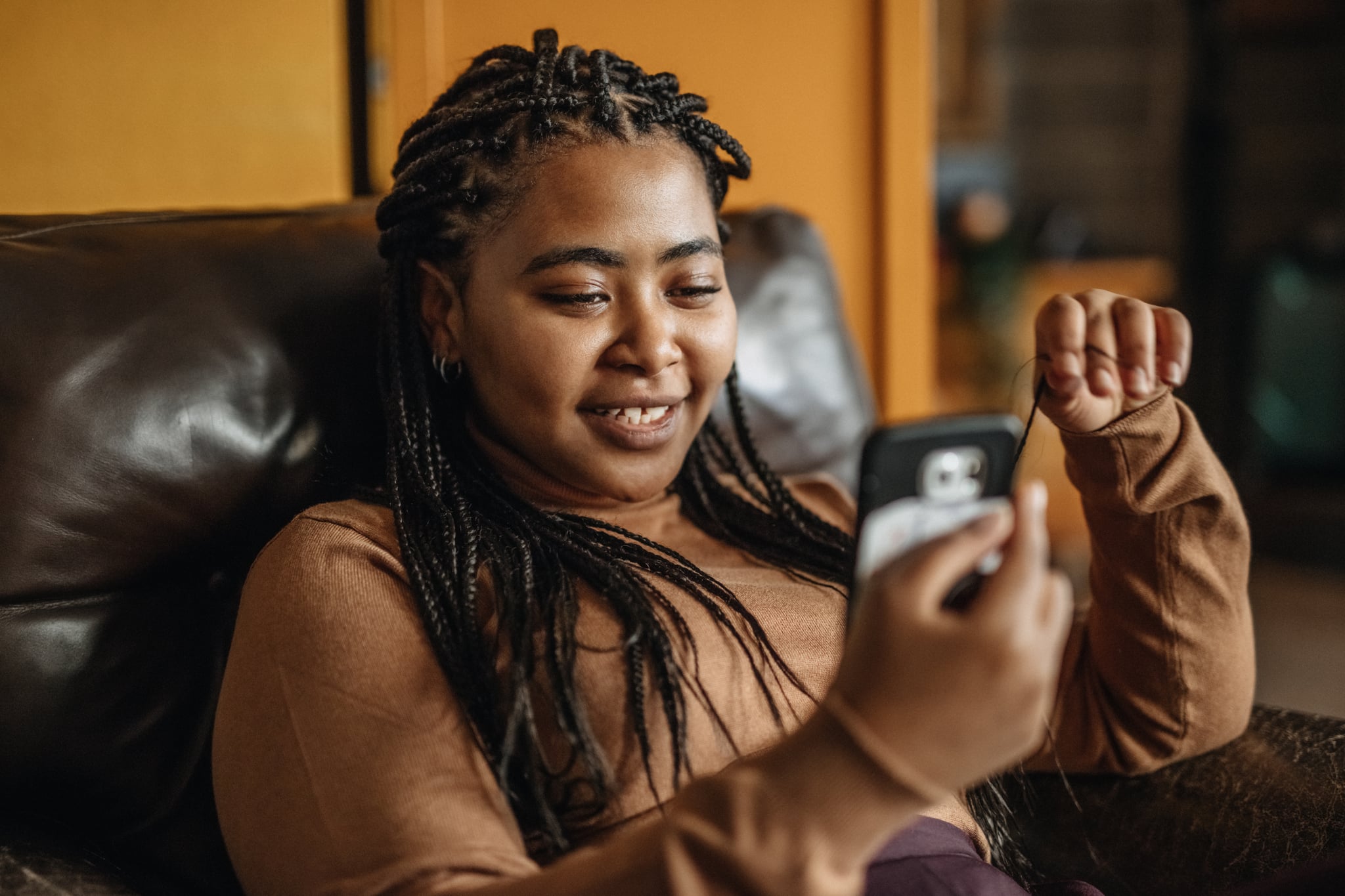 woman sitting on couch looking at phone creating the best bumble bios