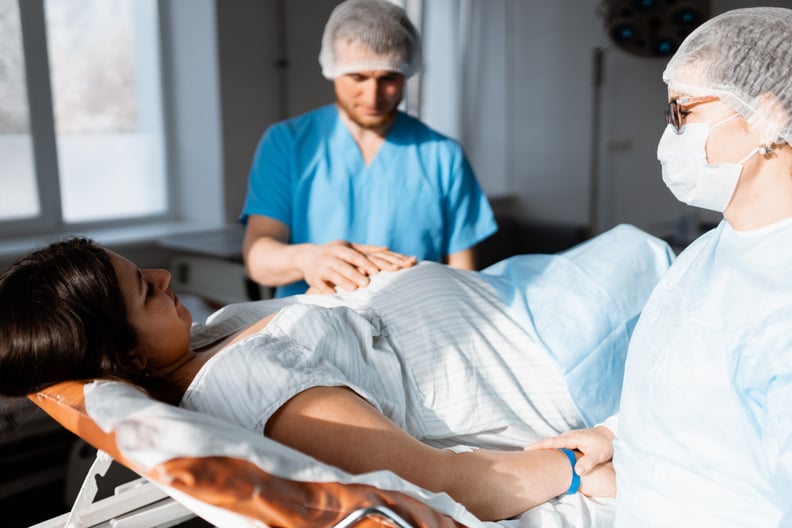 pregnant woman lying in clinic surrounded by doctor and husband