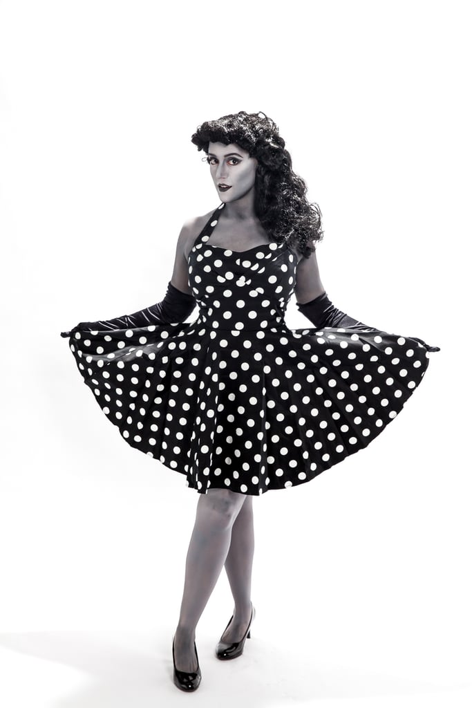 Preparation Is Everything
With any major costume, you’ll want to do your research. With a grayscale costume in particular, you want to make sure that your outfit — and beauty — is perfectly black and white so it doesn’t throw off the whole look. I found the perfect vintage-inspired dress at Modcloth, wore a black wig to hide my light brown hair, and acquired long gloves so I wouldn’t have to paint my fingers . . . or ruin everything I touched. 
While I provided Madison with some reference photos, she said that in the end, she used Pleasantville as her main source of inspiration. I also had initially prepared to wear sheer black tights, but Madison told me painting my legs would look way better. I trusted her instinct, and she was so right.