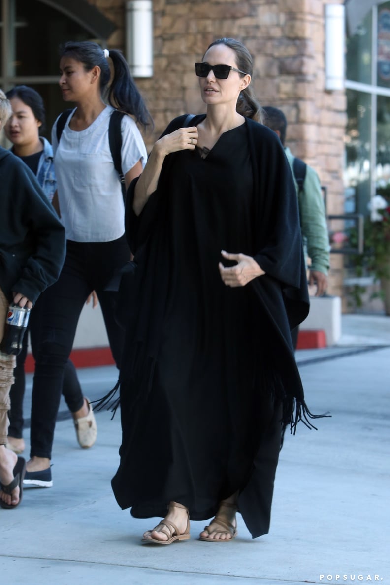 Who made Angelina Jolie's black handbag, brown flat slide sandals