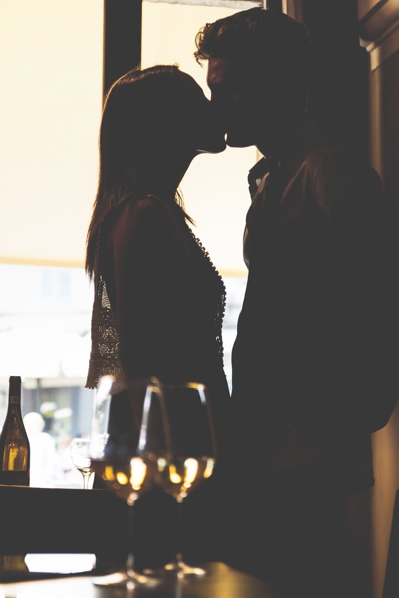 Young lovers kissing in a restaurant. Back lit and foreground blurred.