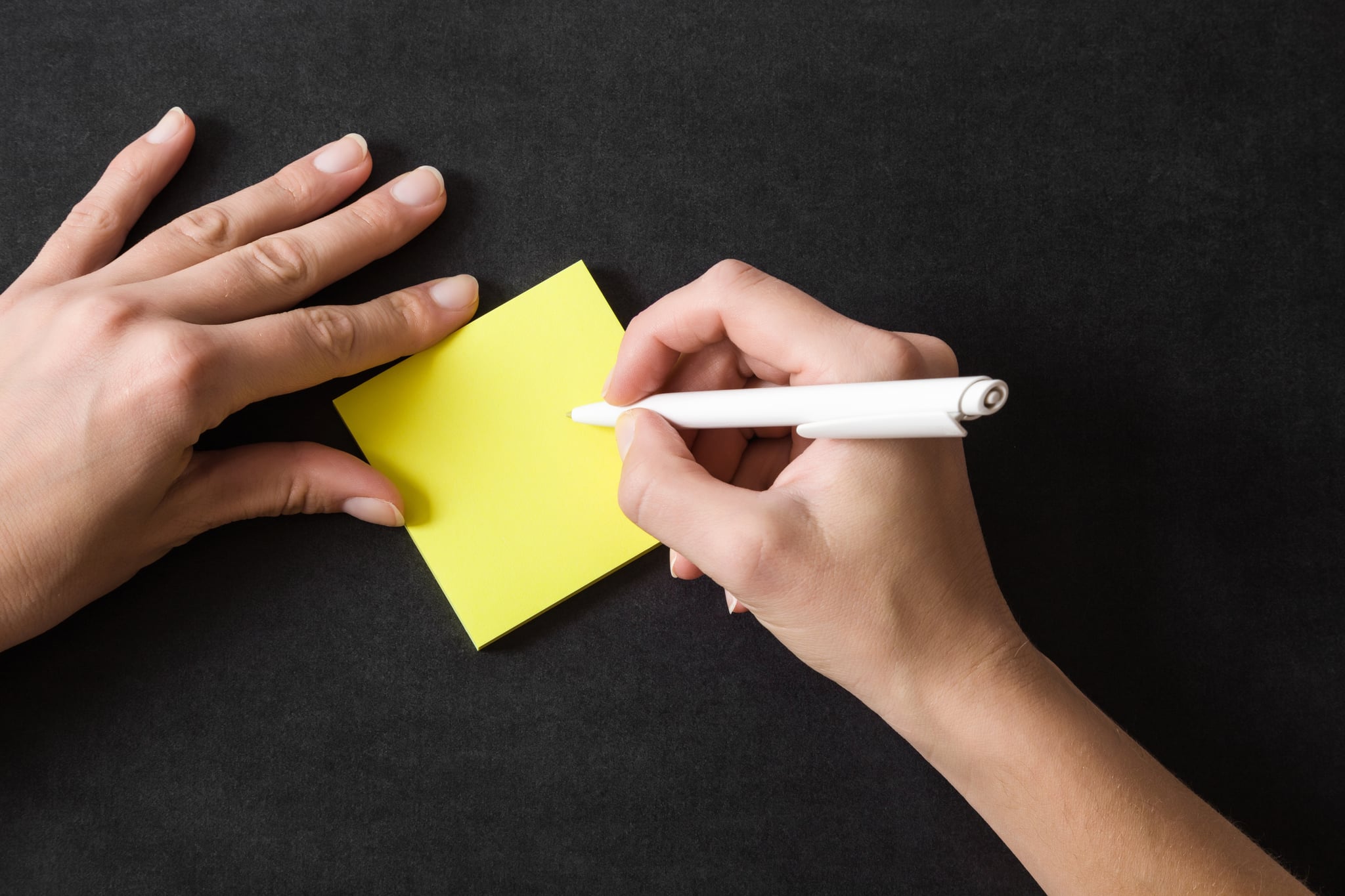Woman writing in the yellow sticky notes. Working on the table. Empty place for a important ideas, plans, memories, messages, compliments or other text with positive mood. Reminder concept.