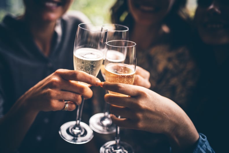 三个女性朋友开香槟庆祝。他们坐在一家酒吧和敬酒杯香槟。