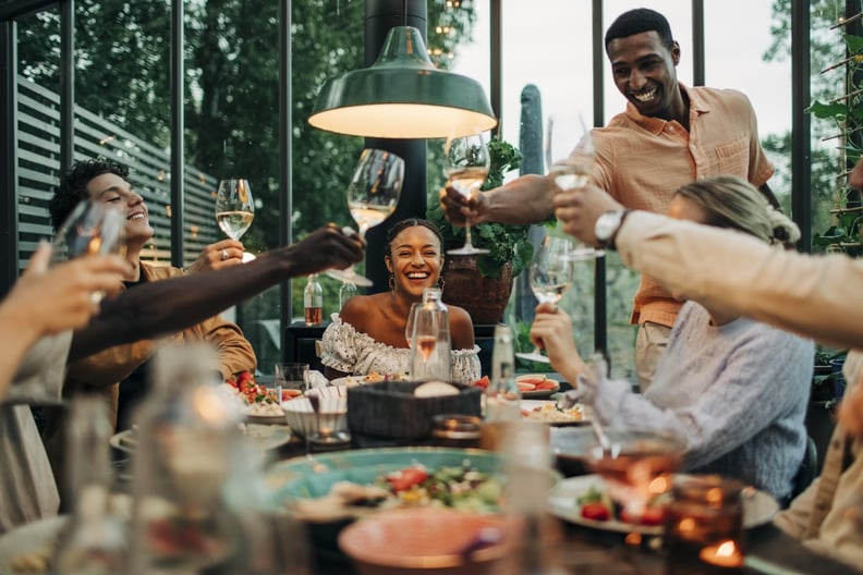 a group of friends toasting wine glasses at dinner