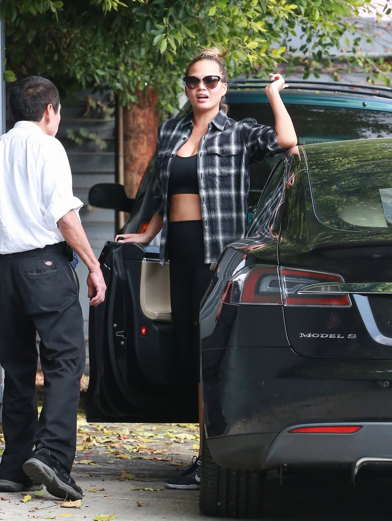 Chrissy kept it sporty in a black sports bra and leggings with a plaid top layered on top.