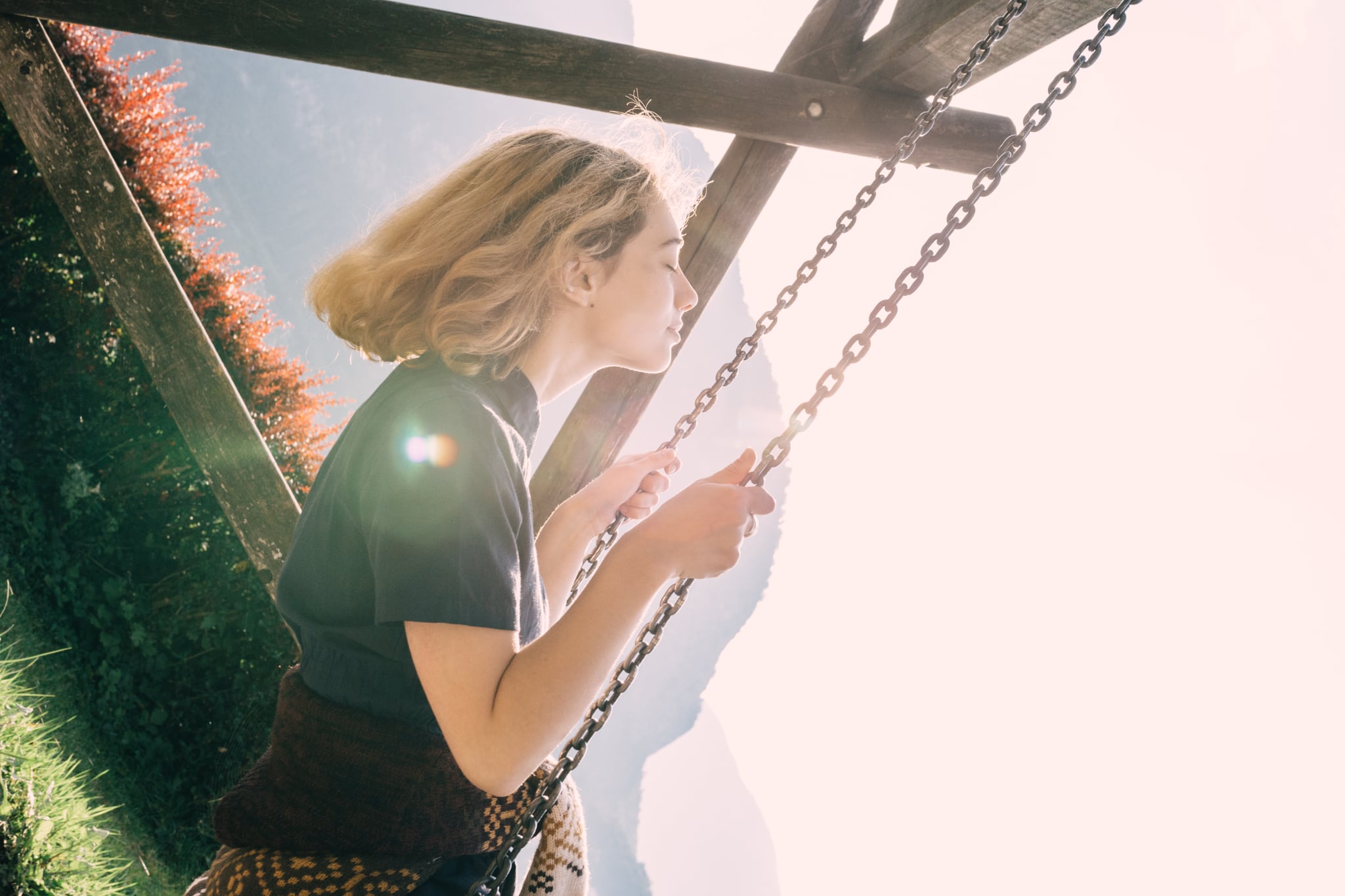 Portrait of young caucasian woman swinging on swing.