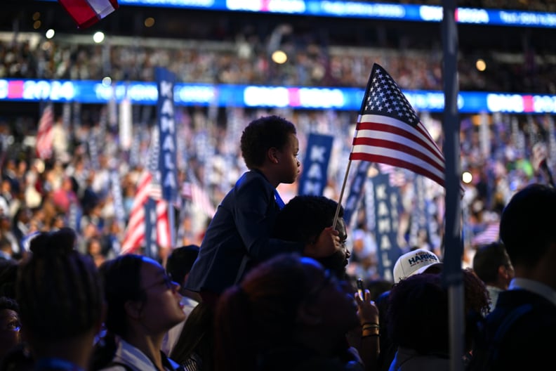 A young attendee holds an American flag as Democratic presidential candidate, U.S. Vice President Kamala Harris speaks onstage during the final day of the Democratic National Convention at the United Center on August 22, 2024 in Chicago, Illinois.