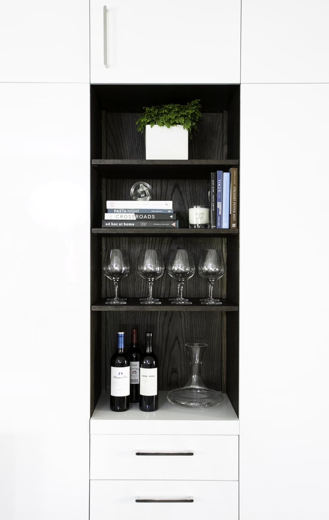 Paneled wood shelves tucked into the cabinets are the perfect place to display wineglasses, and the dark stain contrasts beautifully with the glossy white cabinets.