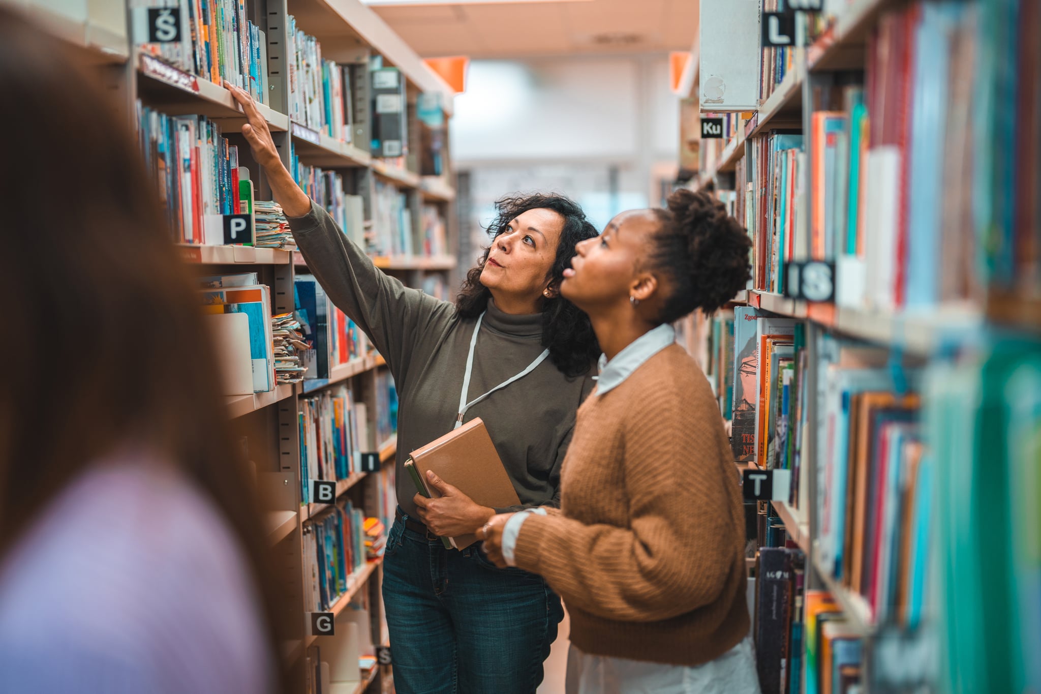 A library card holder asks a librarian for help finding a title at her local branch, where her library card benefits get her lots of free things.
