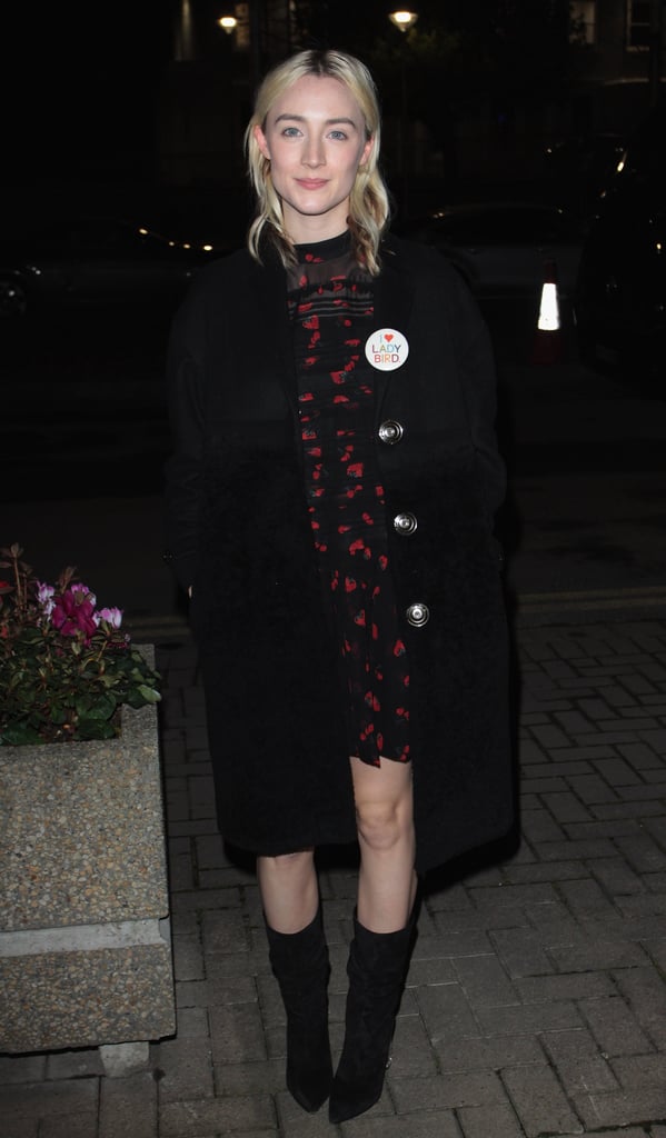 Wearing a printed black dress with a wool coat, black heeled boots, and an "I Love Lady Bird" pin.