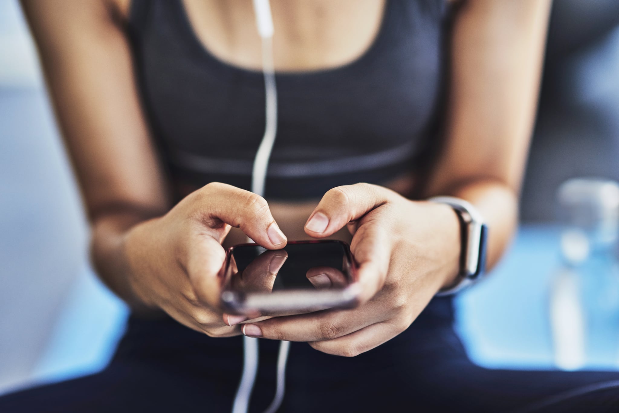 Closeup shot of a sporty woman using a cellphone while exercising in a studio