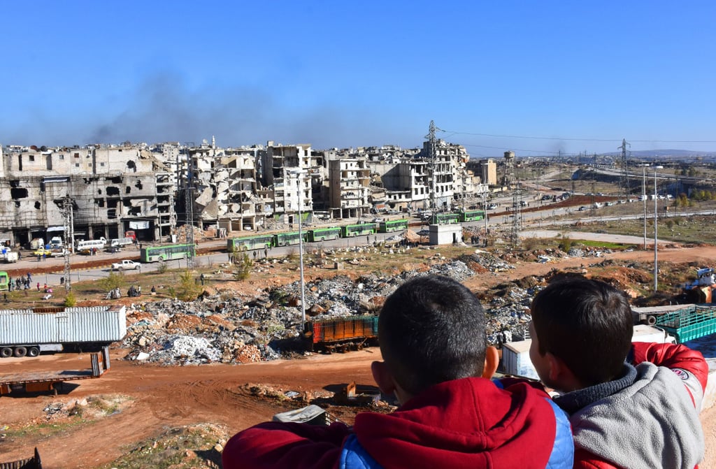 Syrian boys watch as evacuation buses take rebel fighters and their families from Aleppo on Dec. 15.