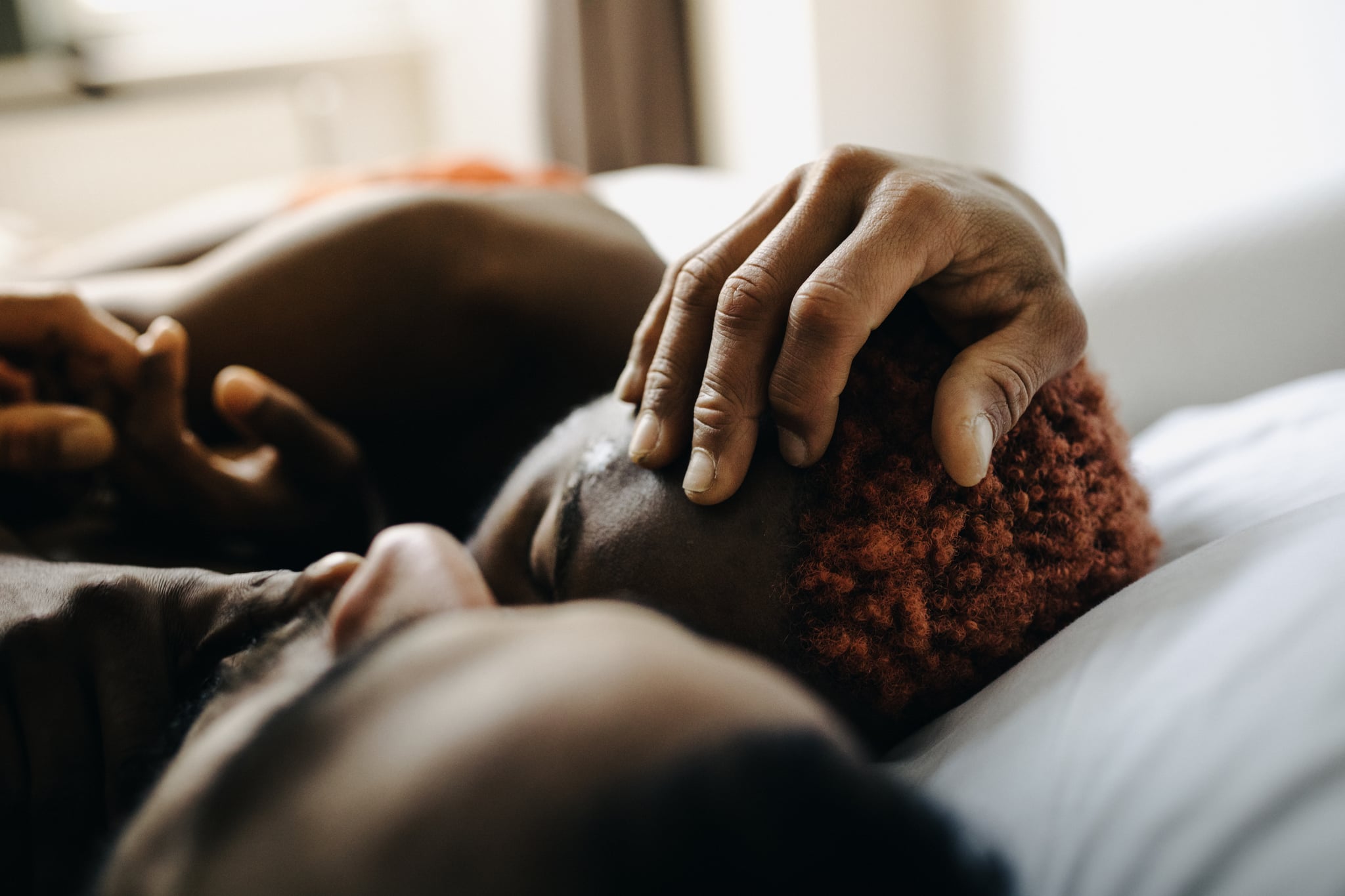 Two men embracing while laying in bed together after meeting up using a dating app.