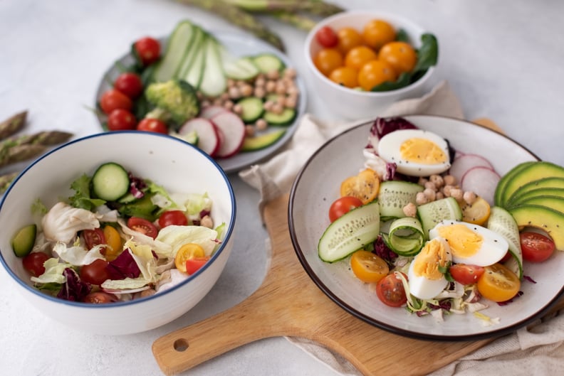 Healthy dish with egg, avocado, quinoa, spinach, fresh tomato, green peas and broccoli on white wooden background, top view