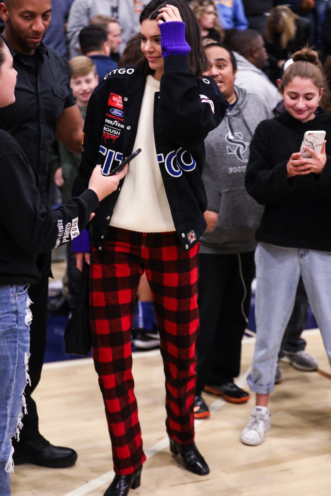 When she sat courtside with friends and sisters Kim and Kourtney at the CIF Open Division Playoffs at Sierra Canyon High School, Kendall showed off her race car love in a patchwork CITGO bomber. She completed her look with red checked pants, black booties, and a colourblock sweater.