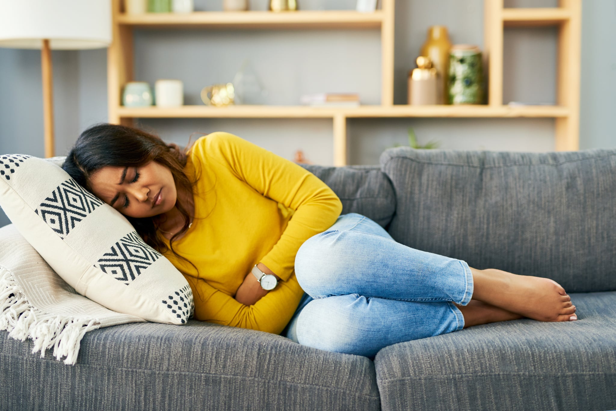 Shot of a young woman suffering from stomach cramps at home