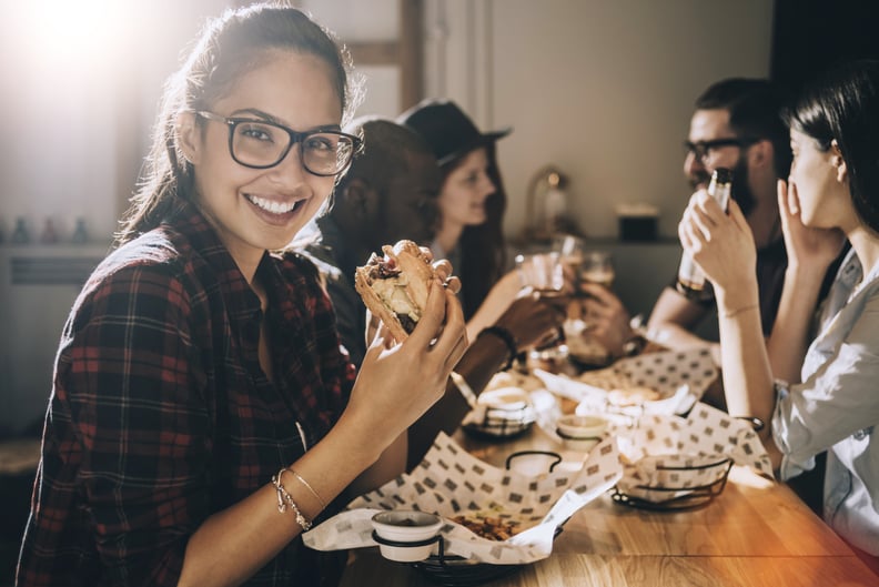 smiling beautiful woman eating a burger and having fun with her friends