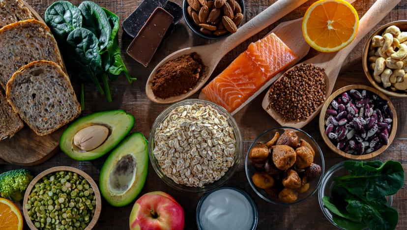 Overhead shot of magnesium-rich foods like avocado, salmon, and oranges.