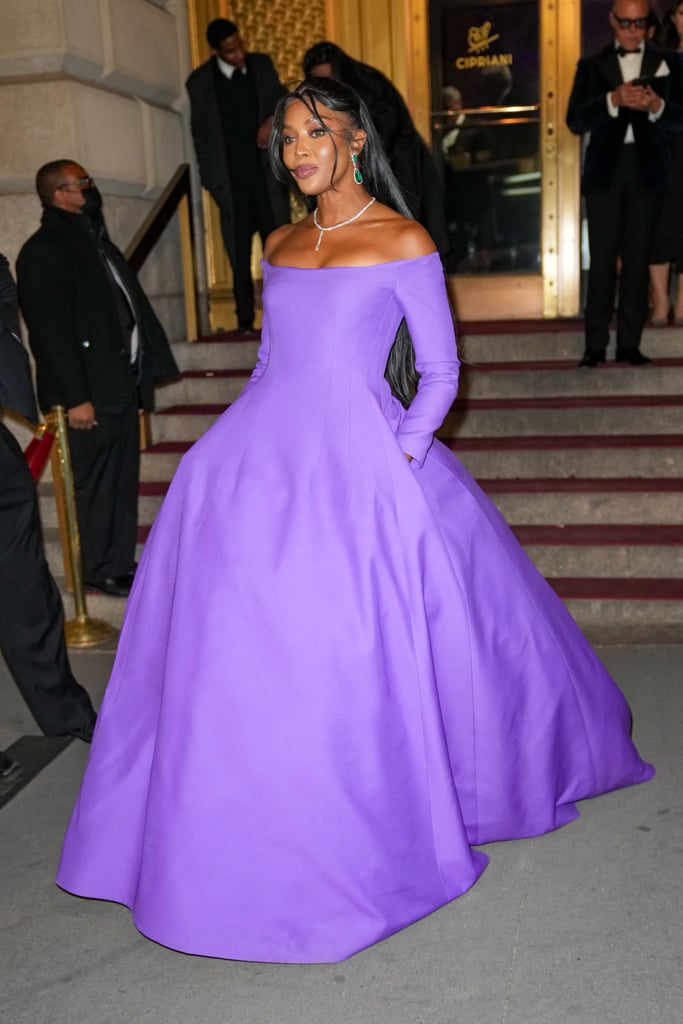 周四晚上，娜奥米·坎贝尔身着皇室礼服出席了在纽约举行的王子信托晚会。借鉴《布里奇顿》的风格手册，坎贝尔身着Maison Valentino露肩礼服和一双配套的紫色厚底高跟鞋走下了铺满红地毯的楼梯。超高的高跟鞋只出现了很短的时间，隐藏在坎贝尔宽大裙子的褶皱下，裙子上还有一组隐藏的口袋。飘逸的拖地裙摆与她半上半下的发型相映成色，这发型瀑布般越过了紧身胸衣的骨架。像一个真正的皇室成员一样，坎贝尔用祖母绿耳环、配套的戒指、无数的手镯和一条钻石项链装饰了她的大圆领口。慈善活动由莱昂内尔·里奇和爱德华·埃宁弗主持，全明星出席，包括贝拉·哈迪德、吉吉·哈迪德、凯特·莫斯、阿杜特·阿凯奇、菲比·戴尼沃、伊曼·哈曼等。这个由英国查尔斯王子于1976年创立的慈善晚会，最近扩展到美国，组织者和捐助人帮助有需要的年轻人提供就业机会和教育培训。看看坎贝尔设计的裙子上所有微妙的细节，包括隐藏的口袋。相关:多芬卡梅伦的蓝色紧身胸衣是直接从“布里奇顿”插曲