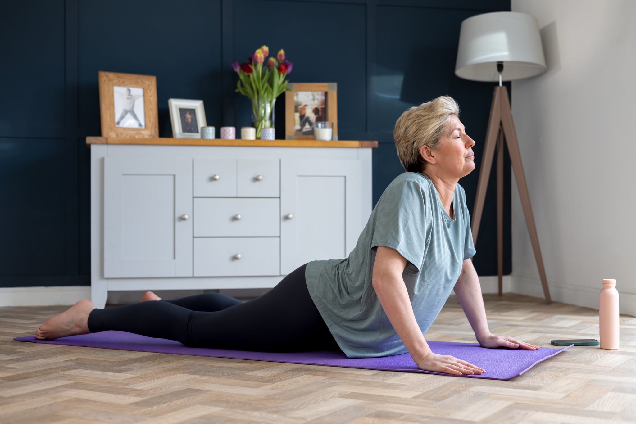 Woman living with breast cancer doing a cobra position on a purple yoga mat. Exercises after mastectomy.