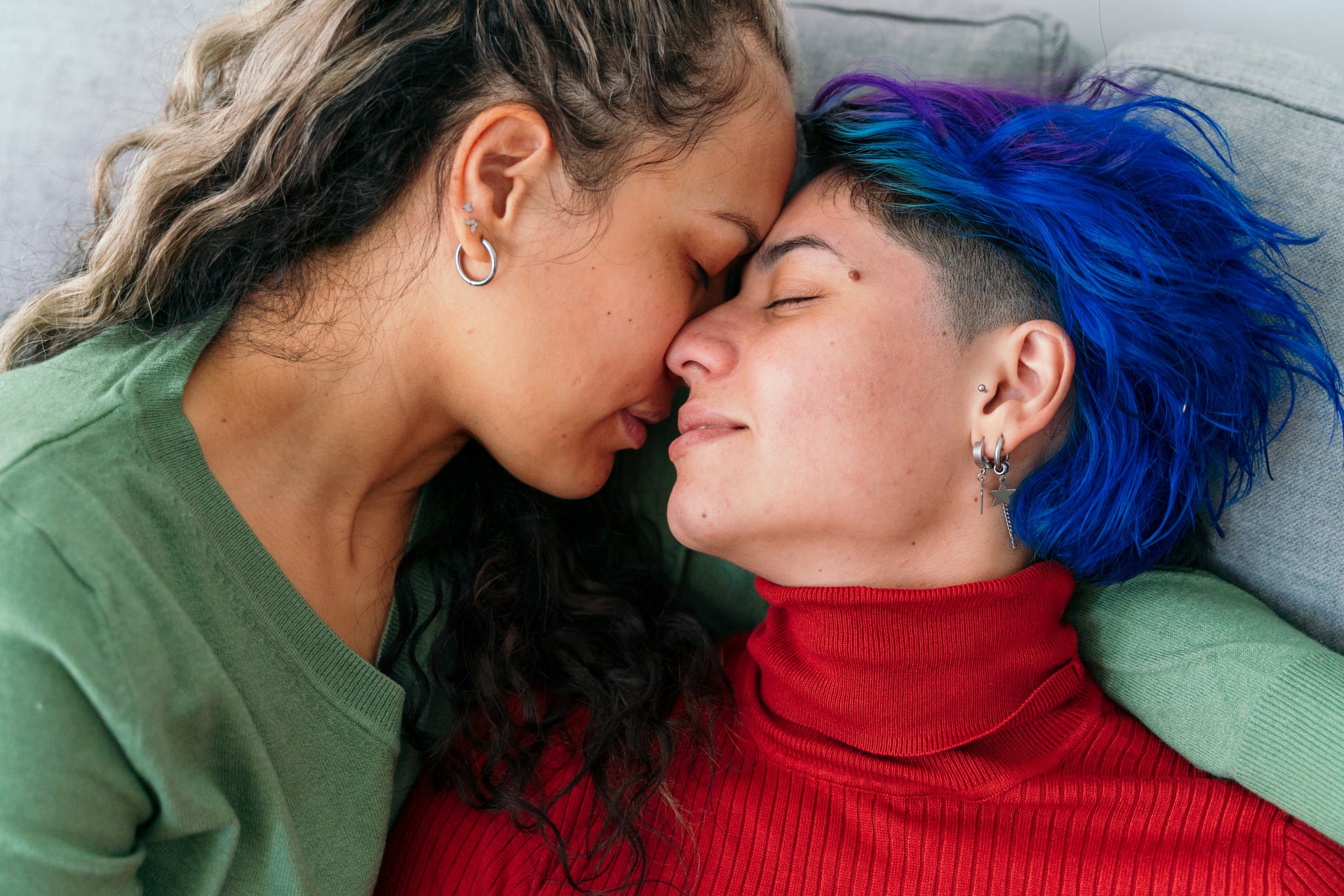水平最高的西班牙裔年轻同性恋女性在家里的沙发上亲吻。Lgbt群体的生活方式在室内。
