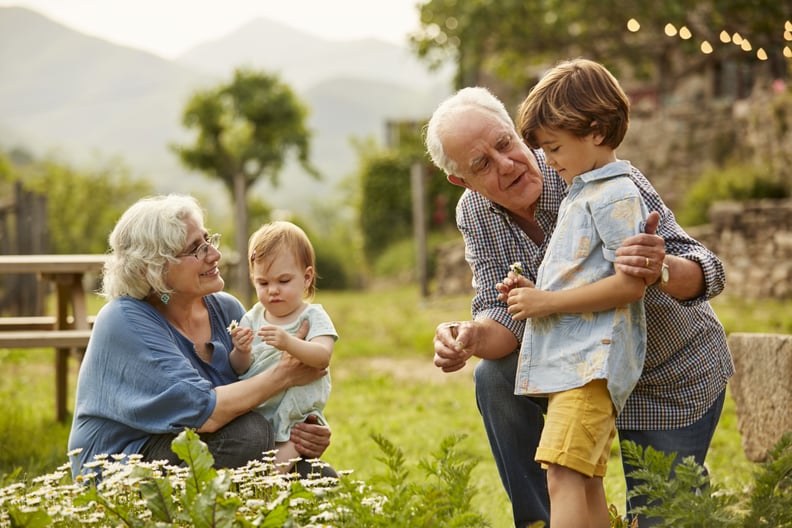 Grandparents talking to children. Family having leisure time in yard. They are wearing casuals.