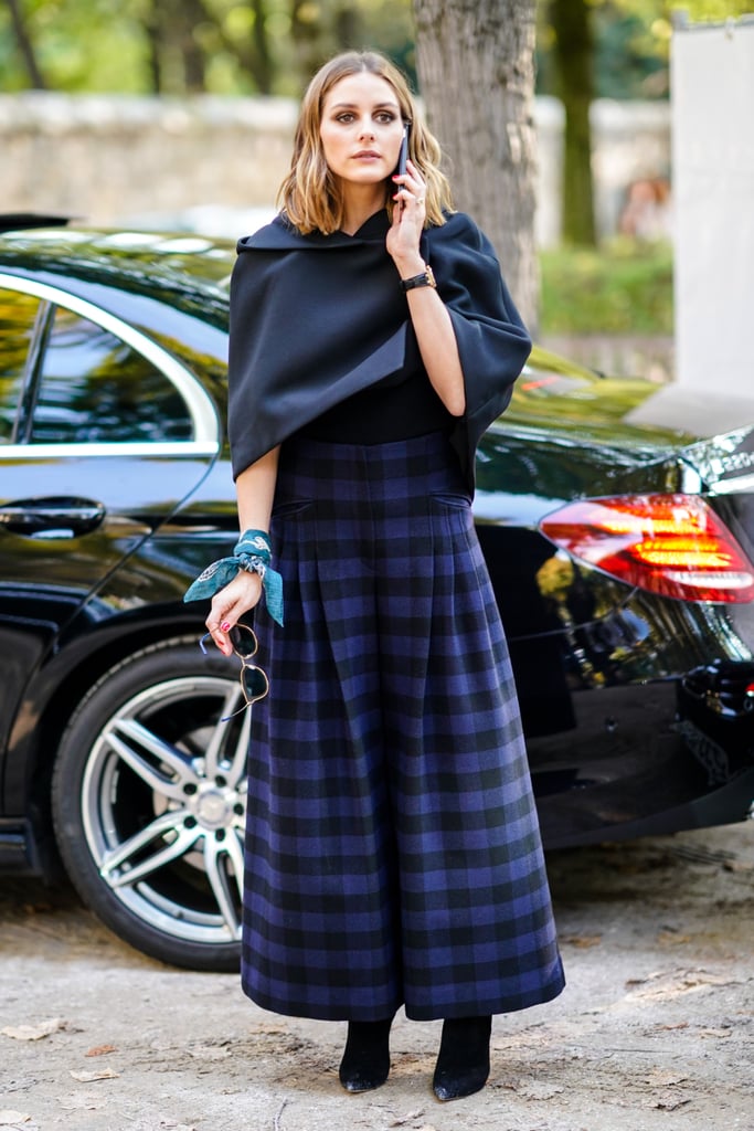 Arriving at the Dior show, Olivia was both modest and statement-making in plaid and a demure cape.